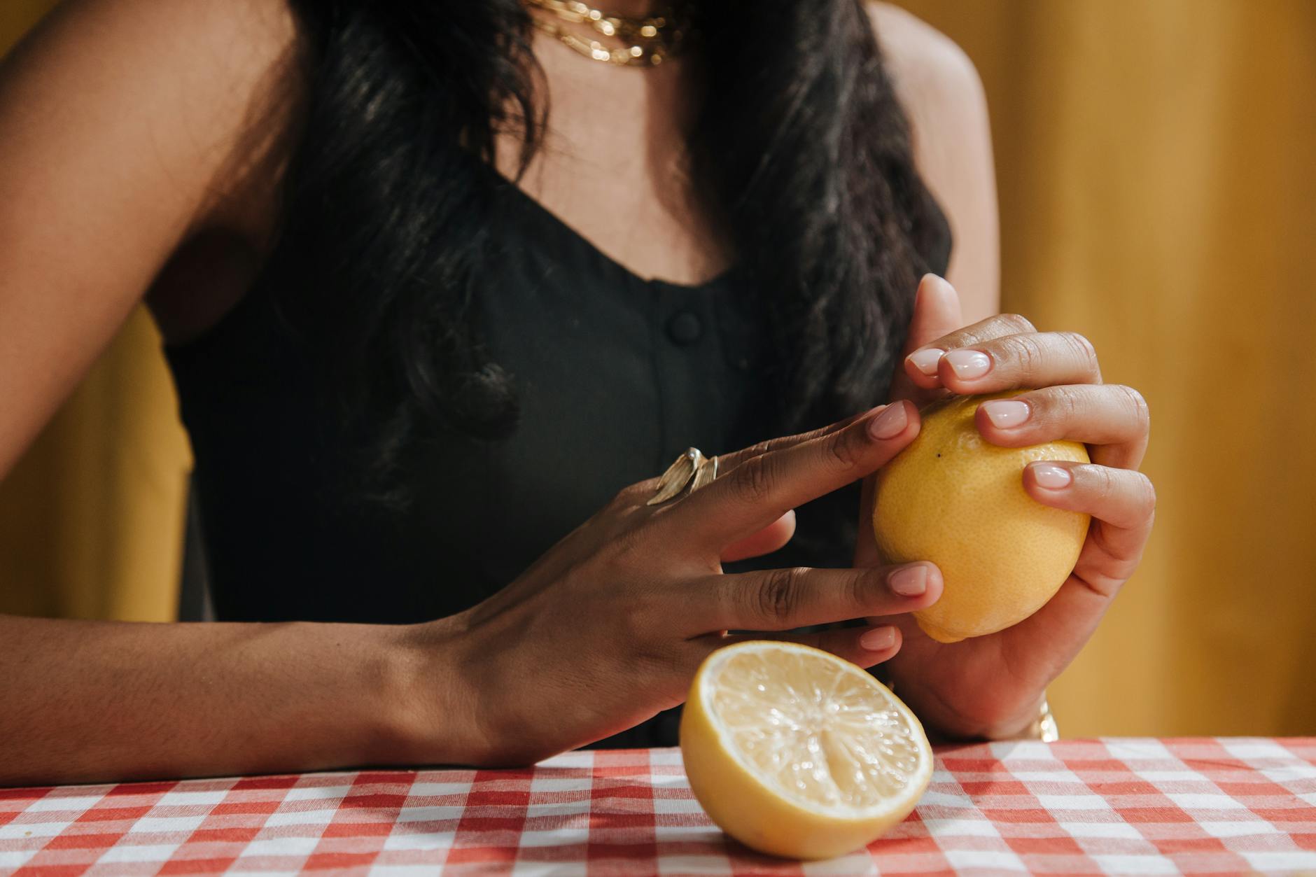 A woman in her thirties thoughtfully holding a fresh lemon, ready to explore new experiences