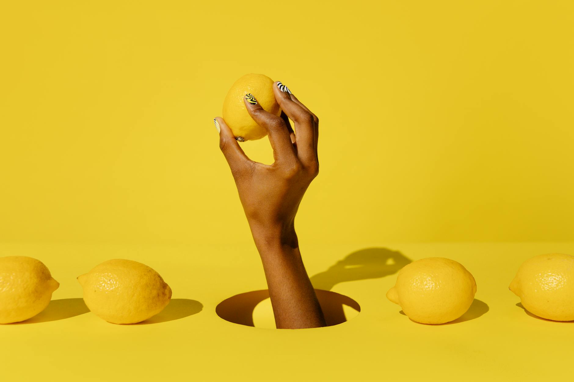 A hand holding a lemon against a vivid yellow background, symbolizing the bright, fresh approach to managing anxiety during intimacy
