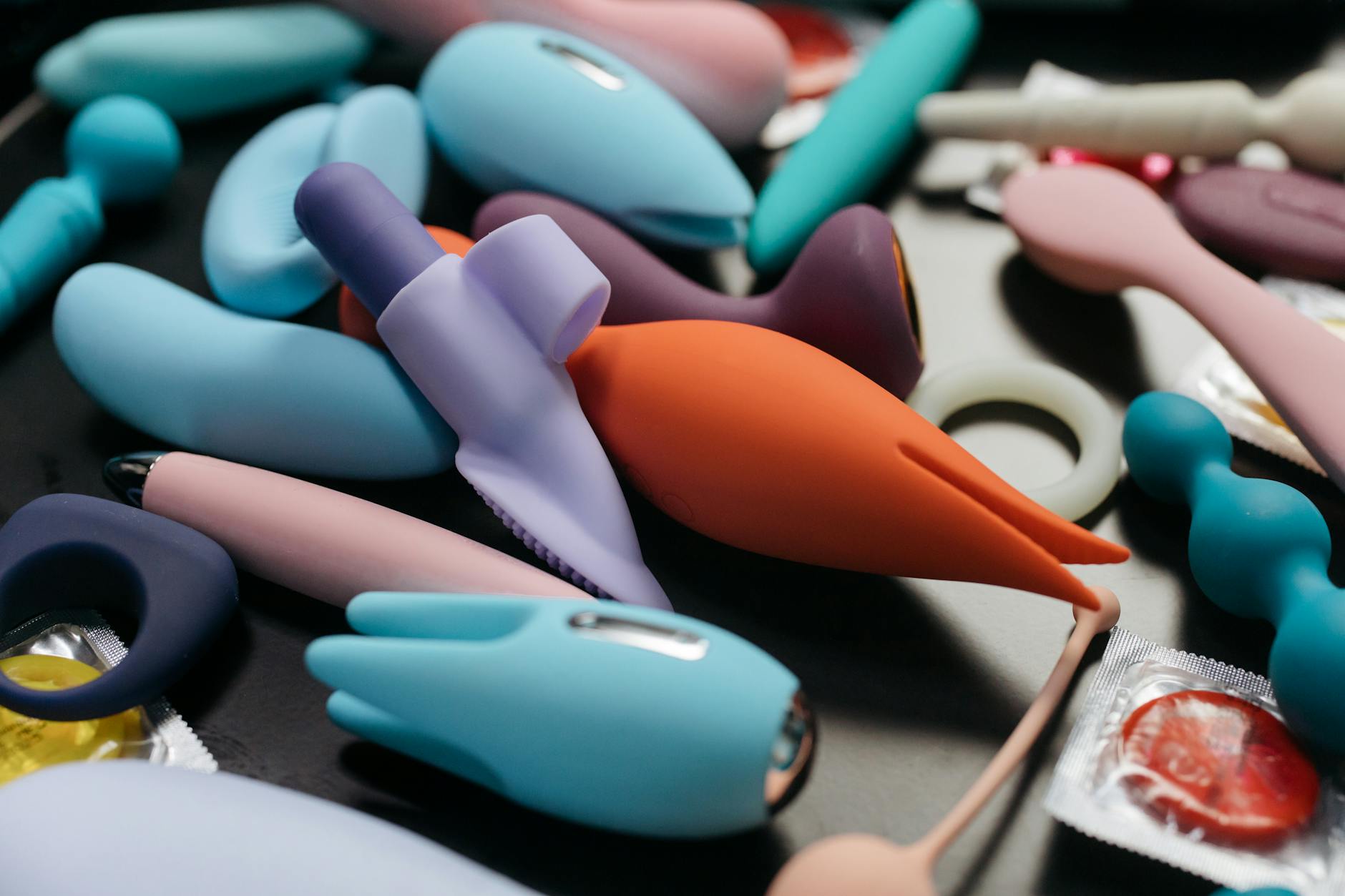 Close-up array of colorful vibrators including a lemon-shaped device on a neutral background