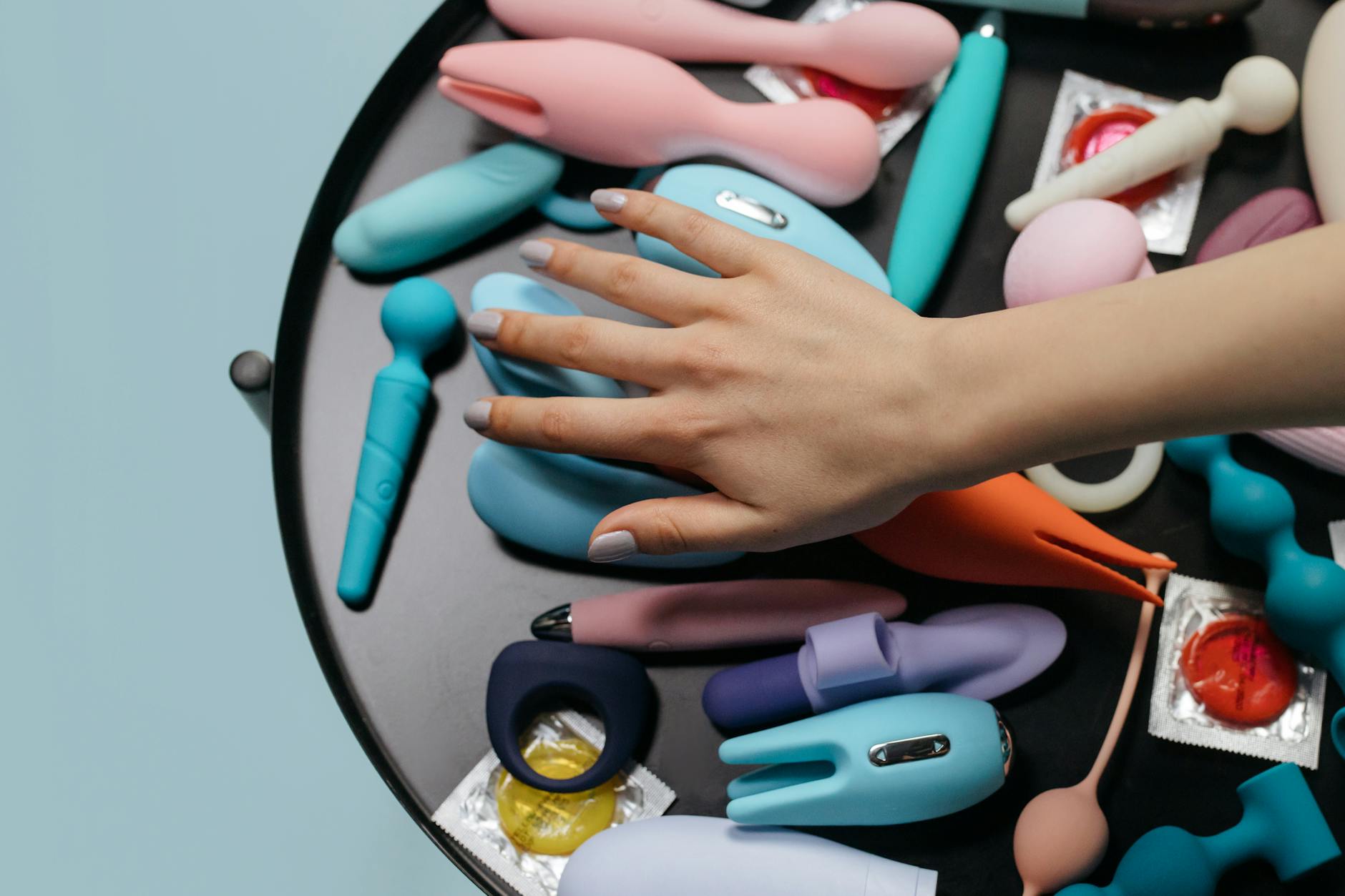 Woman holding colorful vibrators in thoughtful pose