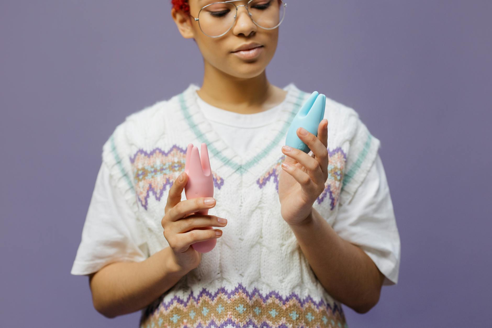 Woman holding a blue and pink silicone vibrator, considering pleasure intentionally