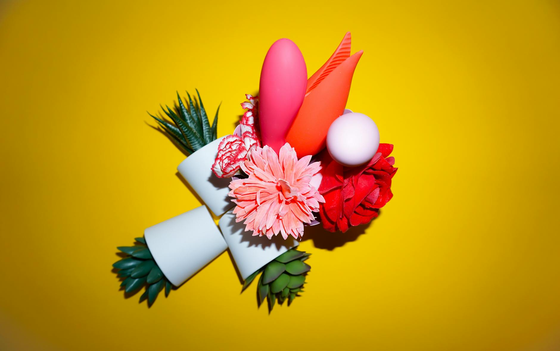 Colorful silicone sex toys arranged on a bright yellow background, showcasing various shapes and designs