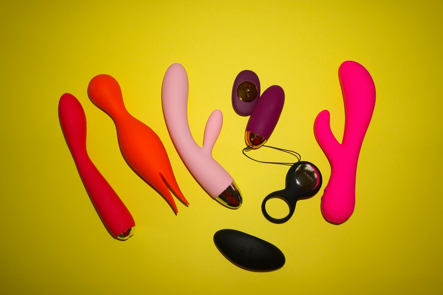 A hand holding a basket containing colorful vibrators and wellness items, symbolizing self-care and intimacy