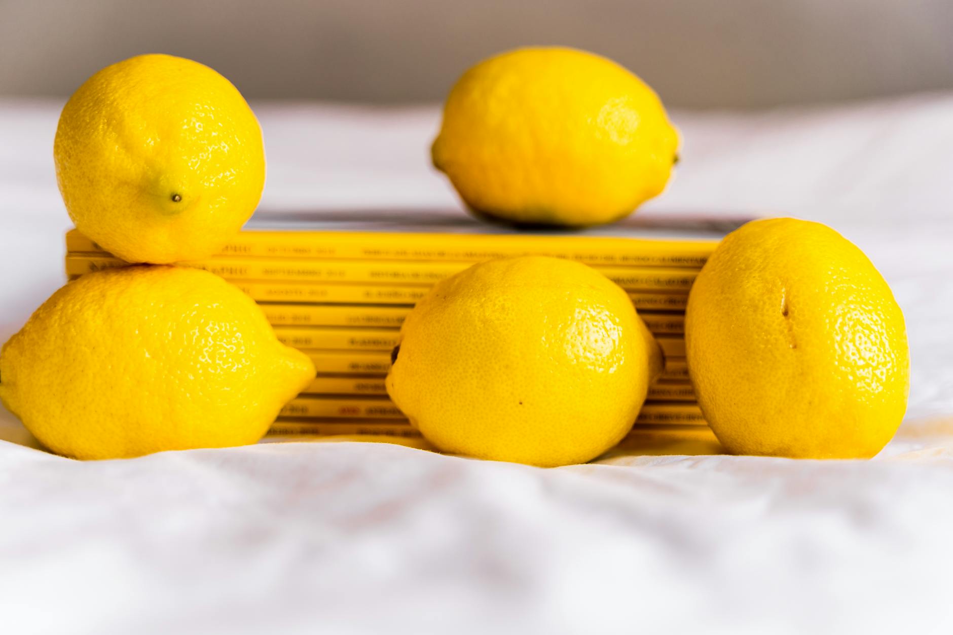 Composizione con limoni freschi interi e libri impilati su una tovaglia bianca